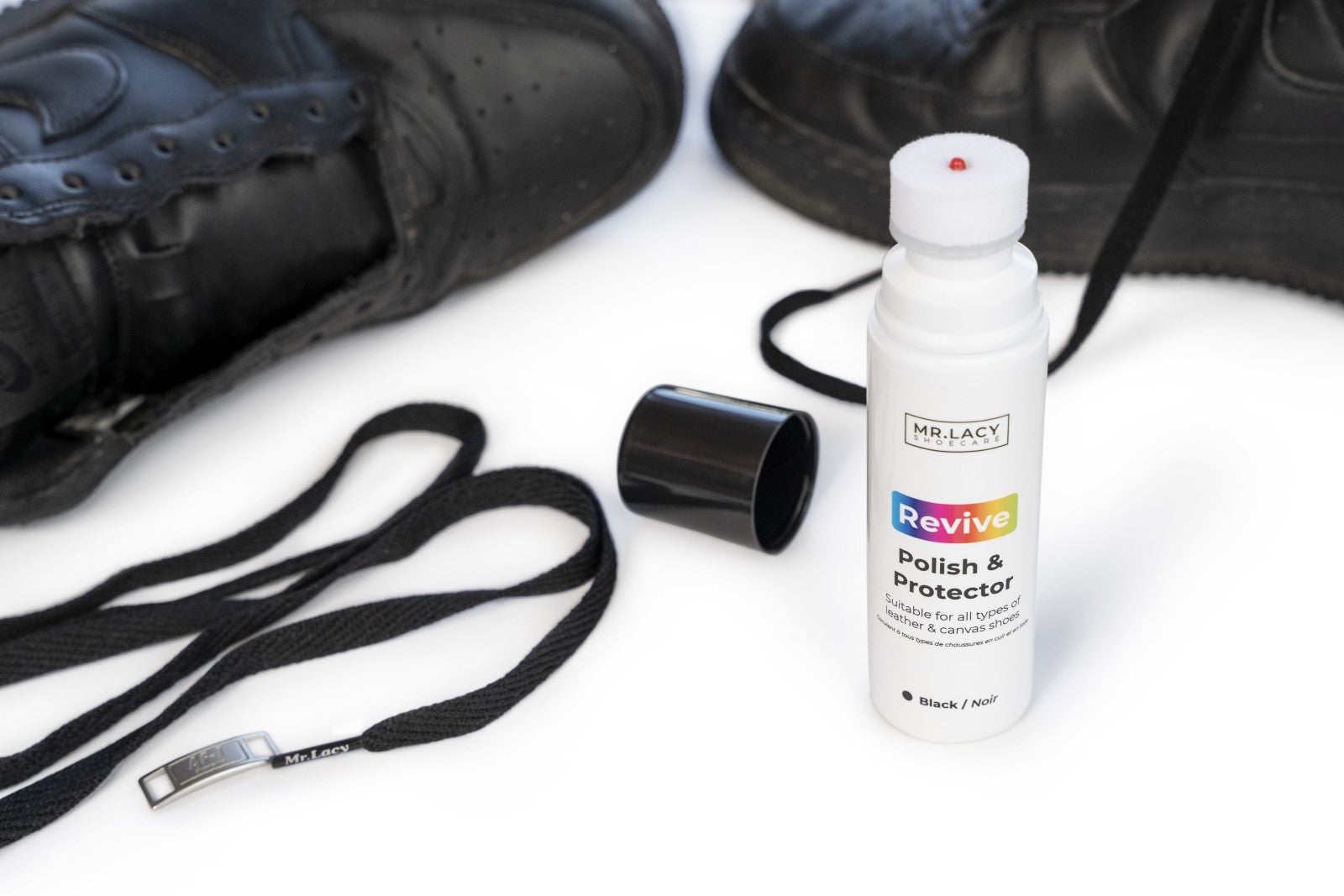 Bottle of Mr. Lacy Revive Polish & Protector with black shoes and laces on a white background